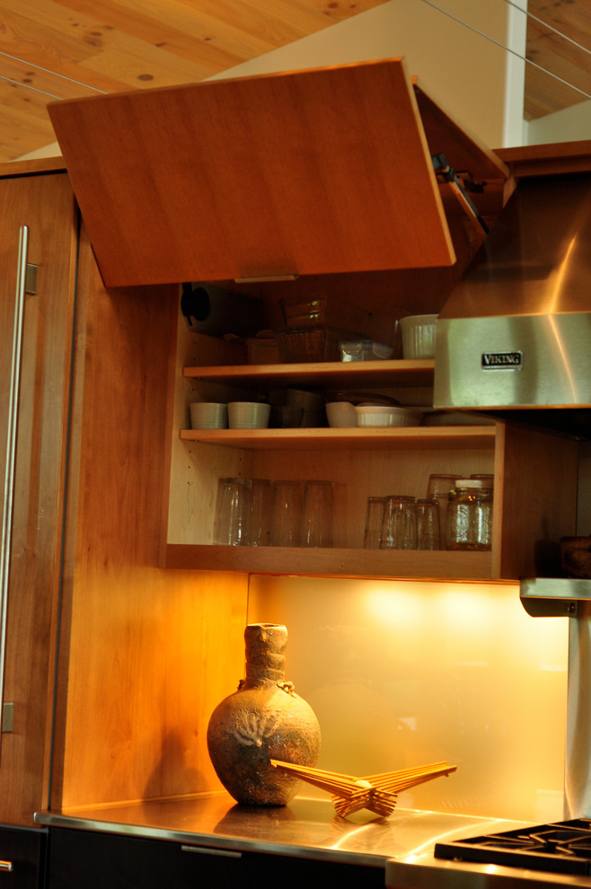 Exempel på ett mellanstort modernt kök, med en dubbel diskho, släta luckor, skåp i mellenmörkt trä, bänkskiva i rostfritt stål, grått stänkskydd, rostfria vitvaror, mellanmörkt trägolv, en halv köksö, brunt golv och spegel som stänkskydd