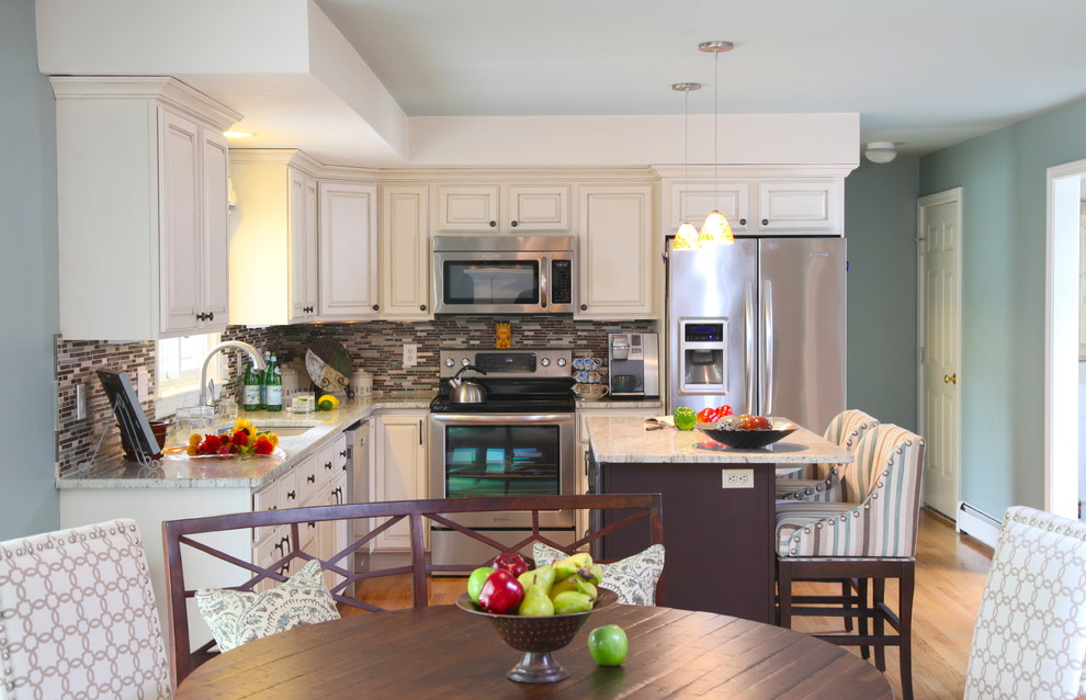 Example of a mid-sized classic l-shaped light wood floor eat-in kitchen design in Boston with an undermount sink, raised-panel cabinets, white cabinets, marble countertops, multicolored backsplash, glass tile backsplash, stainless steel appliances and an island