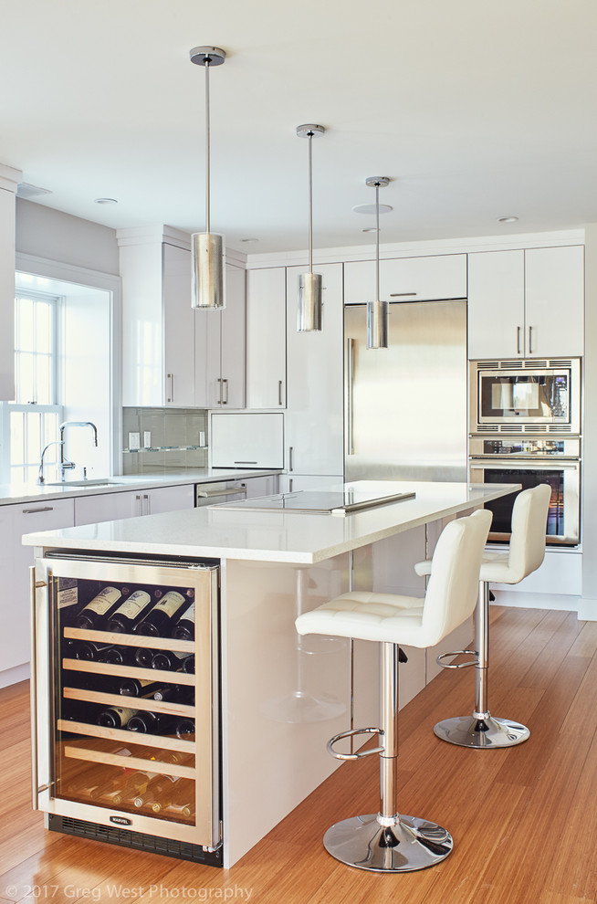 Inspiration for a mid-sized contemporary l-shaped bamboo floor open concept kitchen remodel in Boston with a single-bowl sink, flat-panel cabinets, white cabinets, quartz countertops, gray backsplash, glass tile backsplash, stainless steel appliances and an island