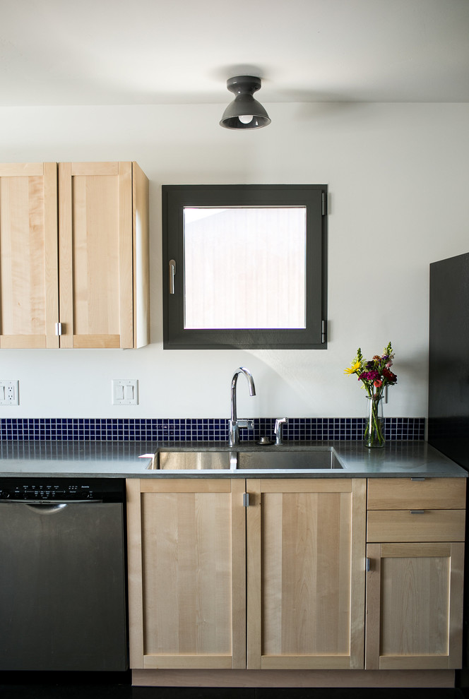 Inredning av ett modernt litet kök, med en undermonterad diskho, skåp i shakerstil, skåp i ljust trä, bänkskiva i betong, blått stänkskydd, stänkskydd i keramik, rostfria vitvaror, betonggolv och grått golv