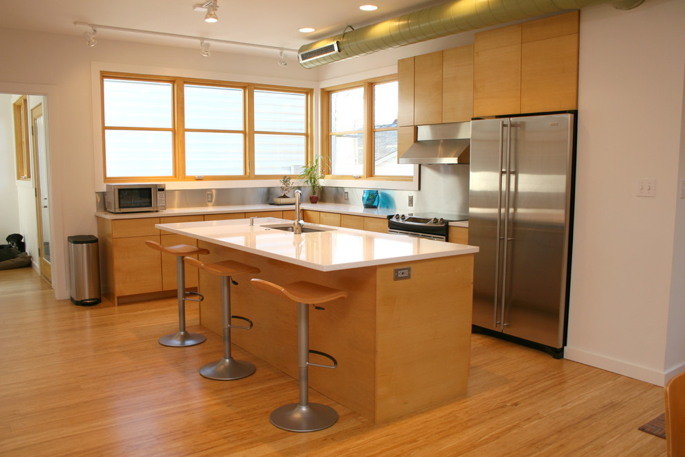 This is an example of a small l-shaped kitchen/diner in St Louis with a submerged sink, flat-panel cabinets, light wood cabinets, metallic splashback, metal splashback, stainless steel appliances, bamboo flooring and an island.