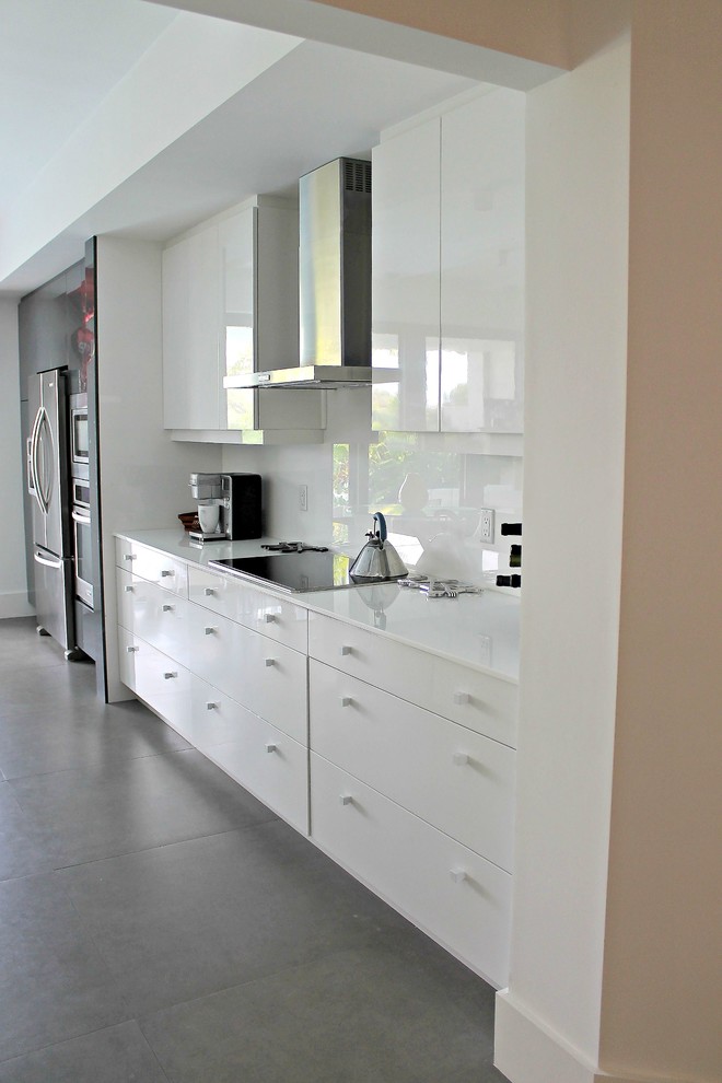 Eklektisk inredning av ett mellanstort linjärt kök och matrum, med släta luckor, vita skåp, vitt stänkskydd, glaspanel som stänkskydd, rostfria vitvaror, betonggolv och grått golv