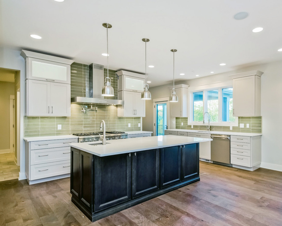 Example of a large minimalist l-shaped medium tone wood floor eat-in kitchen design in Charlotte with a drop-in sink, flat-panel cabinets, white cabinets, quartz countertops, green backsplash, glass tile backsplash, stainless steel appliances and an island