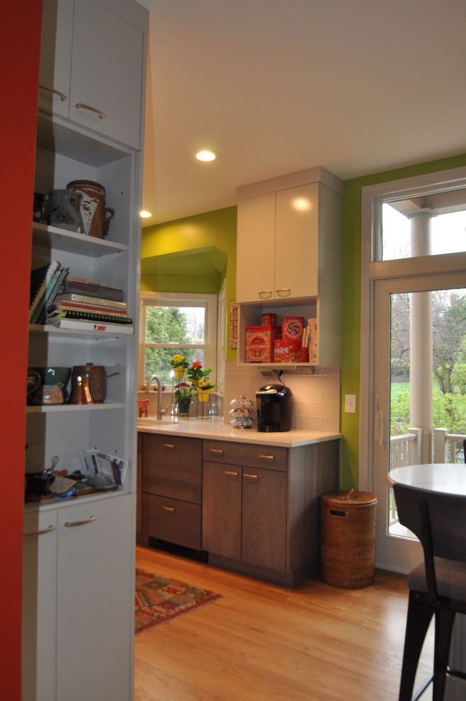 Modern inredning av ett mellanstort kök, med en undermonterad diskho, släta luckor, grå skåp, bänkskiva i kvarts, stänkskydd i glaskakel, rostfria vitvaror, ljust trägolv, en halv köksö och brunt golv