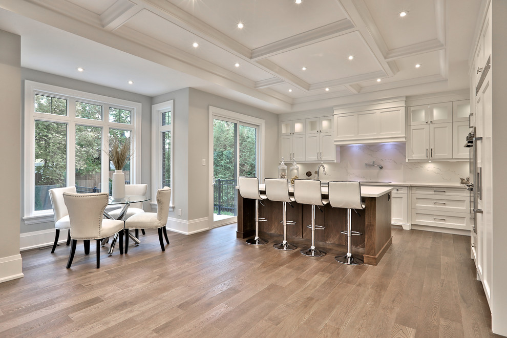 Transitional l-shaped light wood floor and beige floor eat-in kitchen photo in Toronto with shaker cabinets, white cabinets, white backsplash, stone slab backsplash, stainless steel appliances, an island and white countertops