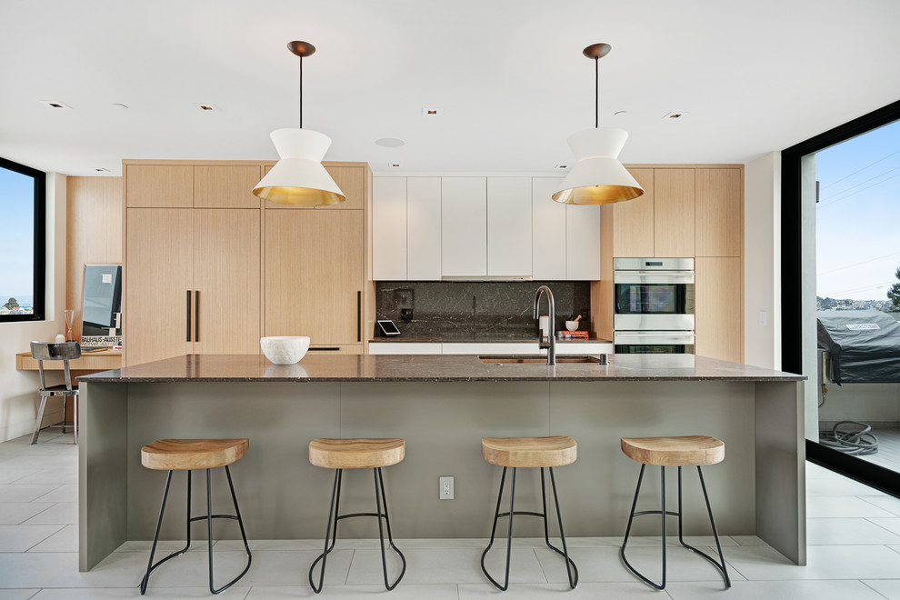Inspiration for a large contemporary galley kitchen/diner in San Francisco with a built-in sink, light wood cabinets, black splashback, stainless steel appliances, an island and grey floors.