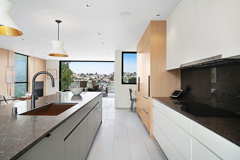 This is an example of a large contemporary galley kitchen/diner in San Francisco with a built-in sink, black splashback, an island and grey floors.