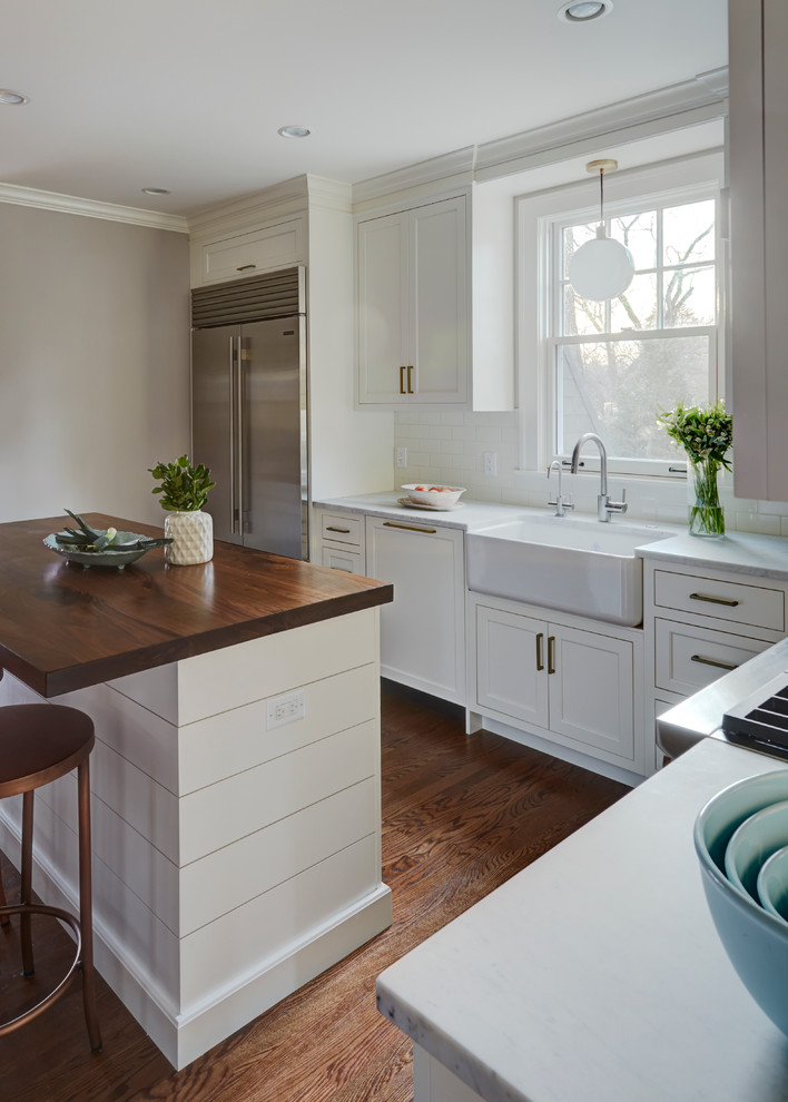 Example of a mid-sized transitional u-shaped kitchen pantry design in Chicago with shaker cabinets, white cabinets, marble countertops, white backsplash and an island