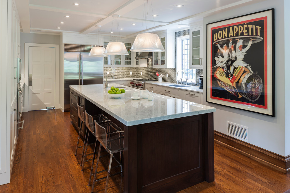 Kitchen - transitional l-shaped kitchen idea in New York with an undermount sink, glass-front cabinets, white cabinets, gray backsplash and stainless steel appliances