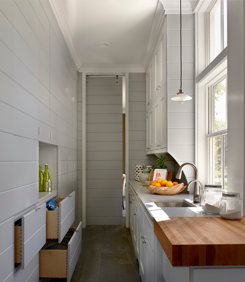 Réalisation d'une cuisine champêtre fermée avec un évier encastré, des portes de placard grises et fenêtre au-dessus de l'évier.