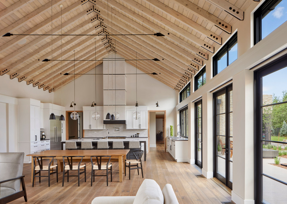 Photo of a large farmhouse u-shaped open plan kitchen in Denver with recessed-panel cabinets, white cabinets, concrete worktops, white splashback, ceramic splashback, stainless steel appliances, medium hardwood flooring, brown floors, grey worktops, an island and a vaulted ceiling.