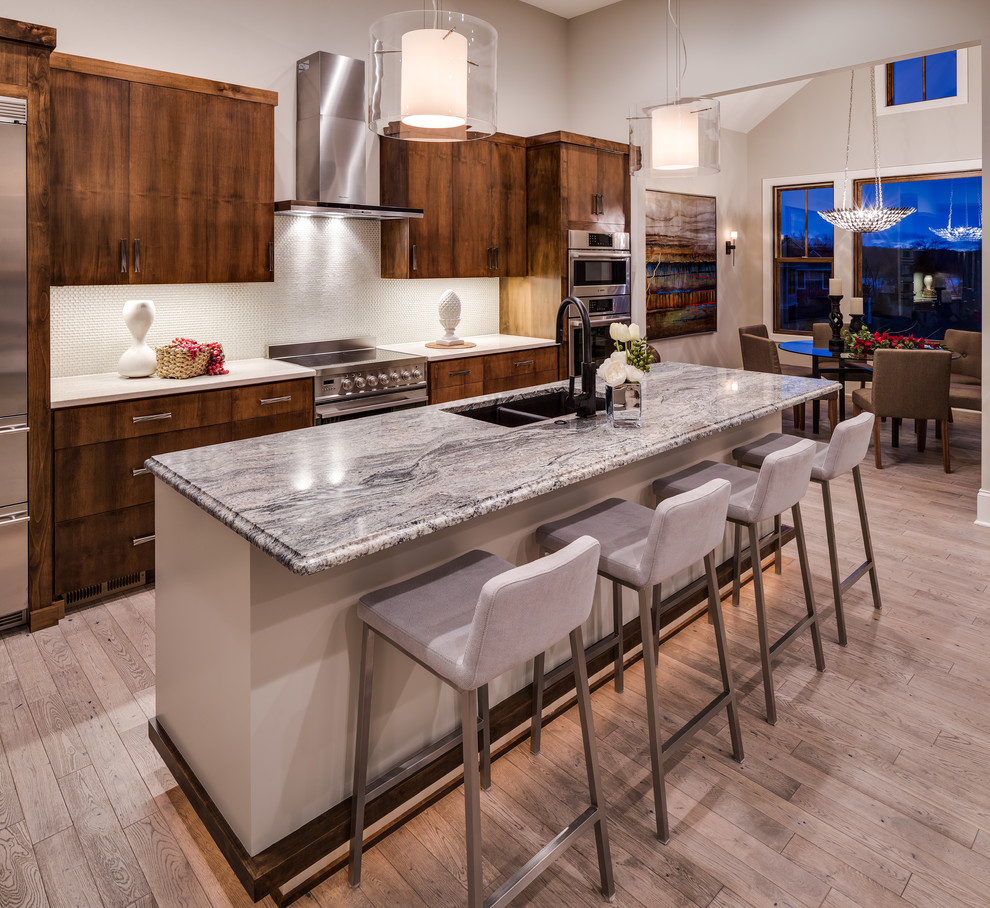This is an example of a medium sized contemporary single-wall kitchen/diner in Minneapolis with a submerged sink, flat-panel cabinets, medium wood cabinets, granite worktops, white splashback, glass tiled splashback, stainless steel appliances, light hardwood flooring and an island.