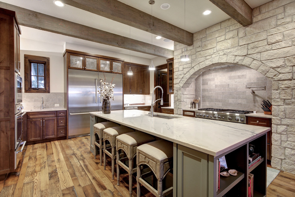 Bild på ett avskilt lantligt u-kök, med en undermonterad diskho, skåp i shakerstil, skåp i mörkt trä, grått stänkskydd, rostfria vitvaror, mellanmörkt trägolv och en köksö