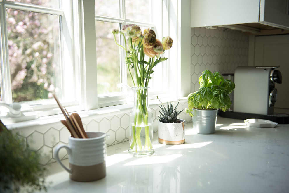 Example of a large country u-shaped light wood floor and brown floor eat-in kitchen design in Boston with shaker cabinets, white cabinets, quartz countertops, white backsplash, mosaic tile backsplash, stainless steel appliances, a peninsula and white countertops