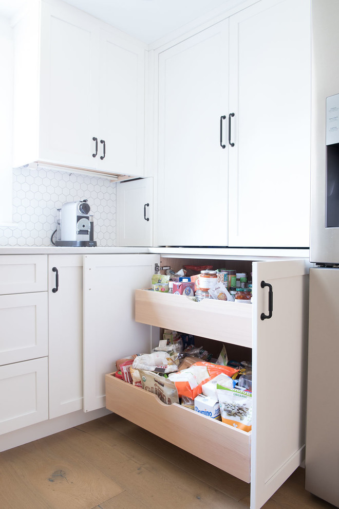 Large farmhouse u-shaped light wood floor and brown floor eat-in kitchen photo in Boston with shaker cabinets, white cabinets, quartz countertops, white backsplash, mosaic tile backsplash, stainless steel appliances, a peninsula and white countertops