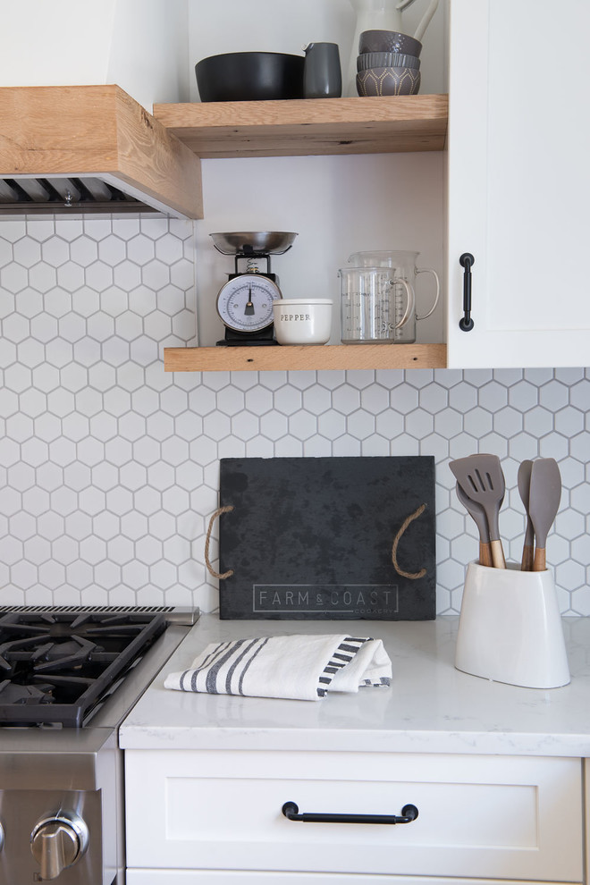 Example of a large farmhouse u-shaped light wood floor and brown floor eat-in kitchen design in Boston with shaker cabinets, white cabinets, quartz countertops, white backsplash, mosaic tile backsplash, stainless steel appliances, a peninsula and white countertops