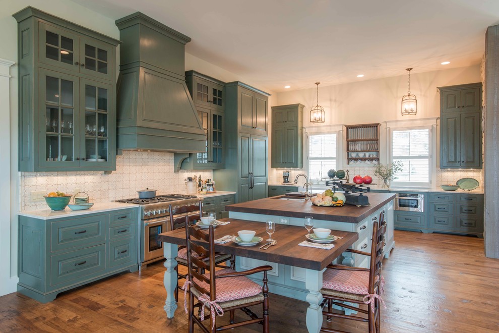 Klassische Küche in L-Form mit profilierten Schrankfronten, blauen Schränken, Küchenrückwand in Weiß, Küchengeräten aus Edelstahl, braunem Holzboden und Kücheninsel in Austin
