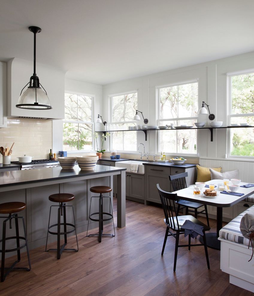 Country eat-in kitchen photo in Austin with a farmhouse sink, recessed-panel cabinets, gray cabinets, beige backsplash, subway tile backsplash and stainless steel appliances