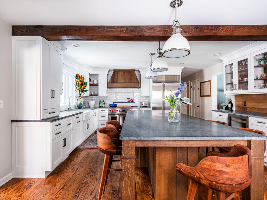 Inspiration for a large farmhouse u-shaped medium tone wood floor and brown floor open concept kitchen remodel in Boston with a farmhouse sink, recessed-panel cabinets, white cabinets, brown backsplash, wood backsplash, stainless steel appliances and an island