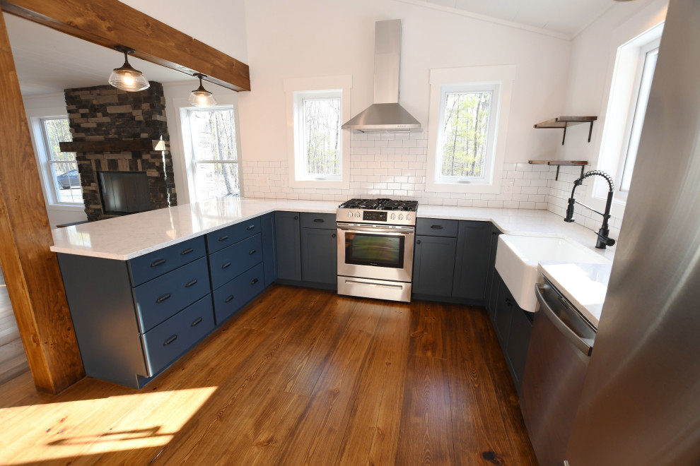 Idéer för att renovera ett mellanstort lantligt vit vitt kök, med en rustik diskho, släta luckor, blå skåp, bänkskiva i kvarts, vitt stänkskydd, stänkskydd i keramik, rostfria vitvaror, mellanmörkt trägolv, en halv köksö och brunt golv