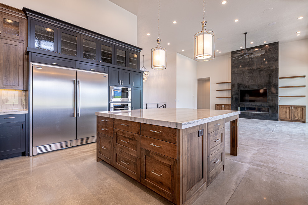 Example of a large country u-shaped concrete floor and gray floor open concept kitchen design in Salt Lake City with an undermount sink, glass-front cabinets, black cabinets, quartzite countertops, beige backsplash, stone slab backsplash, stainless steel appliances, an island and beige countertops