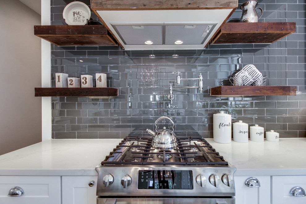 Inspiration for a large cottage u-shaped medium tone wood floor and brown floor eat-in kitchen remodel in Houston with a farmhouse sink, shaker cabinets, white cabinets, quartz countertops, gray backsplash, glass tile backsplash, stainless steel appliances and an island