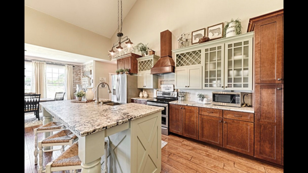 Eat-in kitchen - large country l-shaped laminate floor, brown floor and vaulted ceiling eat-in kitchen idea in Dallas with a farmhouse sink, shaker cabinets, green cabinets, granite countertops, stainless steel appliances, an island and multicolored countertops