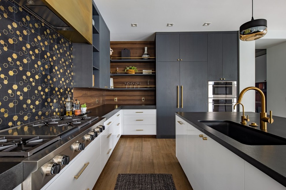 Bild på ett funkis svart svart l-kök, med en undermonterad diskho, släta luckor, vita skåp, rostfria vitvaror, mellanmörkt trägolv, en köksö och brunt golv