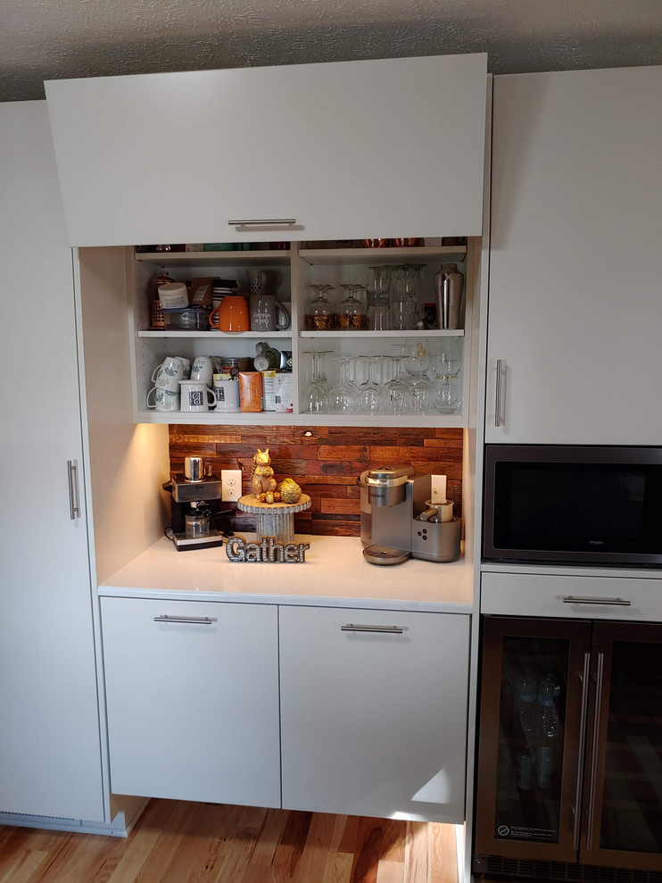 Bild på ett mellanstort lantligt vit vitt kök och matrum, med en undermonterad diskho, släta luckor, vita skåp, bänkskiva i kvarts, brunt stänkskydd, stänkskydd i trä, rostfria vitvaror och ljust trägolv