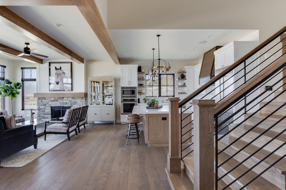 Example of a country l-shaped light wood floor kitchen design in Salt Lake City with a farmhouse sink, shaker cabinets, white cabinets, white backsplash, subway tile backsplash, stainless steel appliances, an island, white countertops and quartzite countertops
