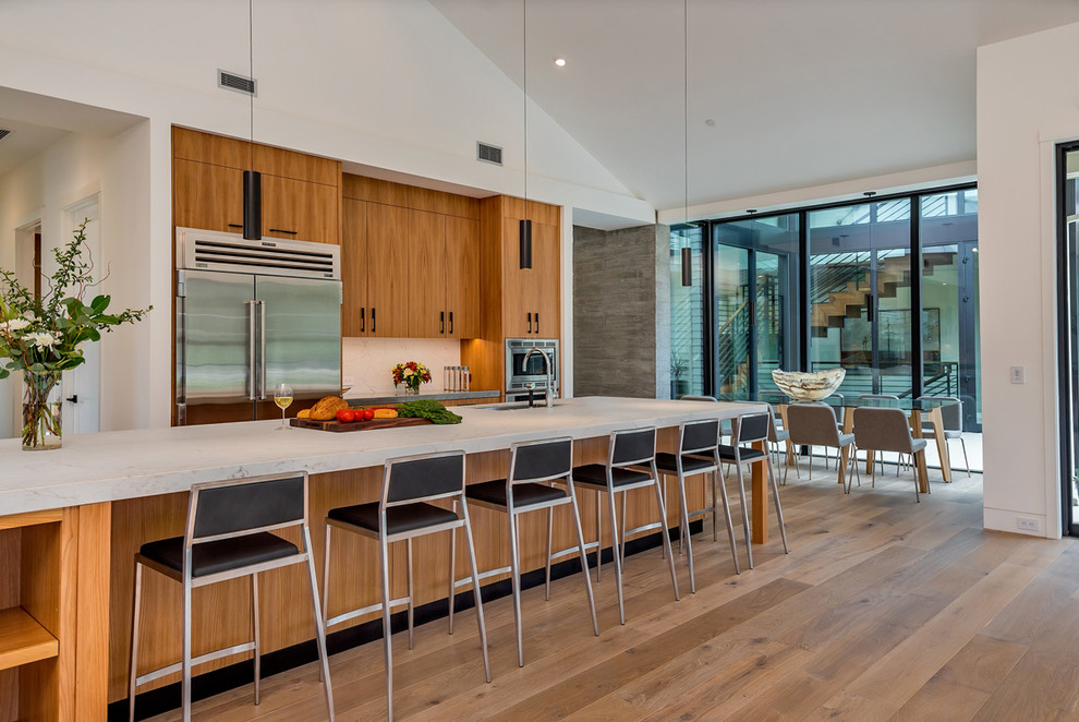 Moderne Wohnküche mit flächenbündigen Schrankfronten, hellen Holzschränken, Küchengeräten aus Edelstahl, hellem Holzboden und Kücheninsel in San Francisco