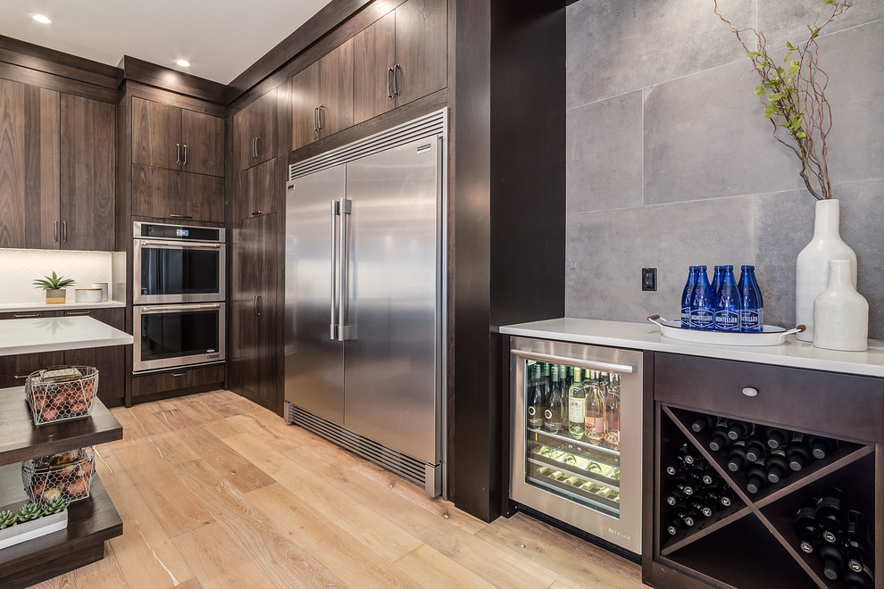 Example of a large country l-shaped light wood floor and beige floor eat-in kitchen design in Calgary with an undermount sink, flat-panel cabinets, dark wood cabinets, quartz countertops, white backsplash, subway tile backsplash, stainless steel appliances and an island