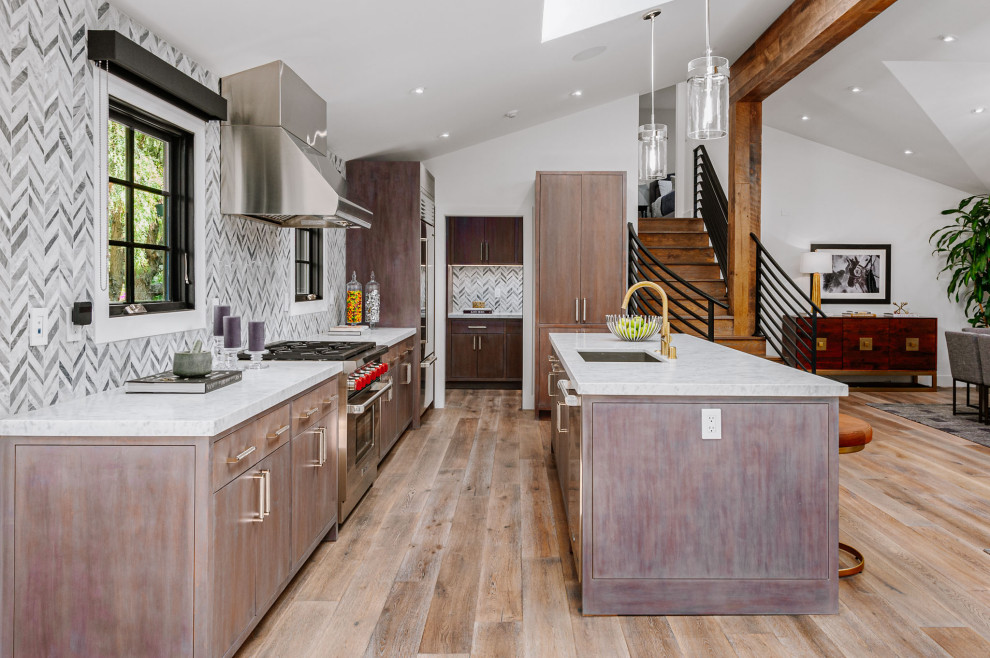 Idéer för att renovera ett mycket stort lantligt grå linjärt grått kök med öppen planlösning, med en undermonterad diskho, luckor med infälld panel, skåp i mörkt trä, marmorbänkskiva, stänkskydd i stickkakel, rostfria vitvaror, mellanmörkt trägolv och en köksö