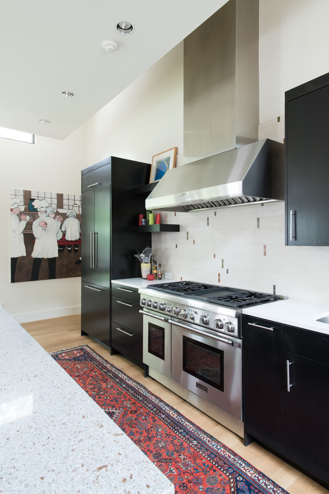 Bild på ett mellanstort funkis kök, med en rustik diskho, släta luckor, skåp i mörkt trä, bänkskiva i kvarts, svart stänkskydd, stänkskydd i porslinskakel, rostfria vitvaror, ljust trägolv och en köksö