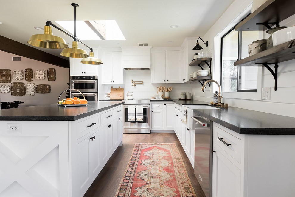 Landhausstil Küche in L-Form mit Landhausspüle, Schrankfronten im Shaker-Stil, weißen Schränken, Küchengeräten aus Edelstahl, dunklem Holzboden, Kücheninsel, braunem Boden und schwarzer Arbeitsplatte in Sacramento