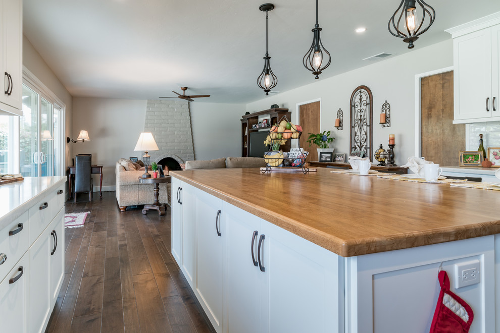 Inspiration for a large farmhouse l-shaped dark wood floor and brown floor open concept kitchen remodel in Other with a farmhouse sink, shaker cabinets, white cabinets, granite countertops, white backsplash, subway tile backsplash, stainless steel appliances, an island and gray countertops