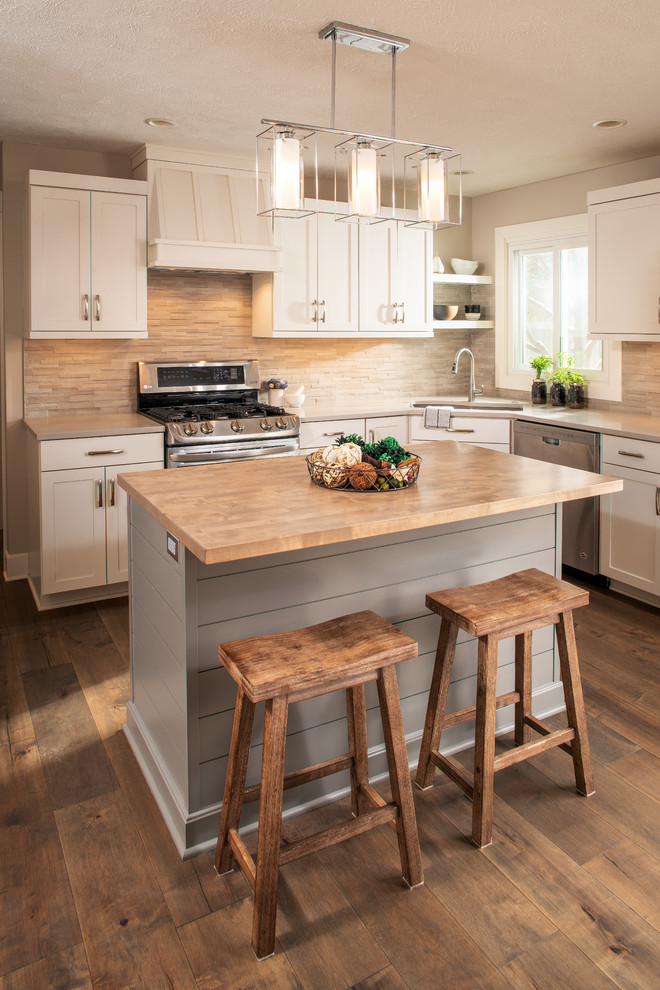 Inspiration for a mid-sized farmhouse u-shaped medium tone wood floor and brown floor eat-in kitchen remodel in Omaha with an undermount sink, shaker cabinets, white cabinets, quartz countertops, gray backsplash, stone tile backsplash, stainless steel appliances, an island and white countertops