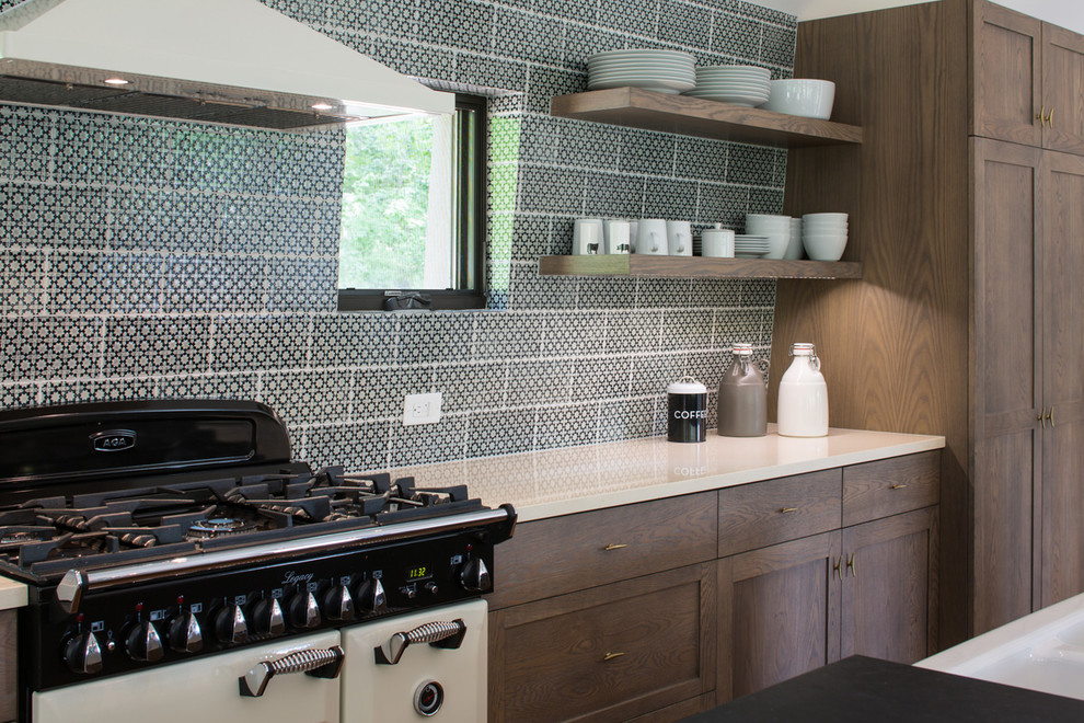 Inspiration for a large rustic single-wall medium tone wood floor eat-in kitchen remodel in Other with a farmhouse sink, shaker cabinets, medium tone wood cabinets, solid surface countertops, multicolored backsplash, ceramic backsplash, stainless steel appliances and an island