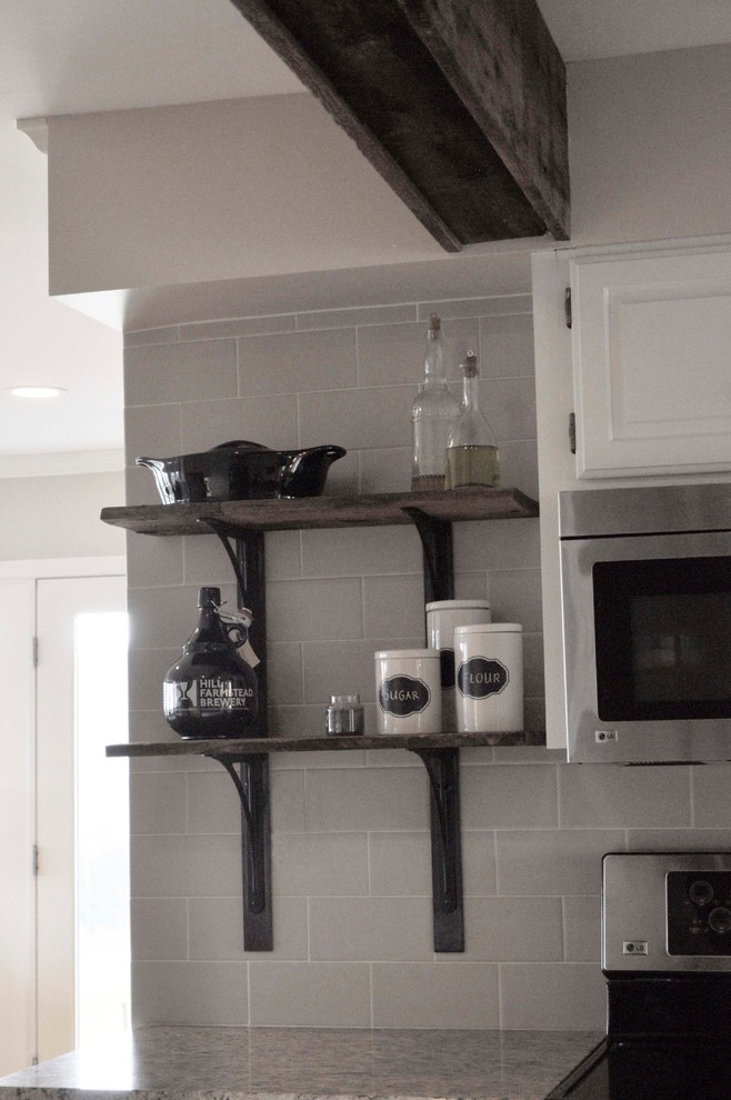 Exempel på ett mellanstort lantligt kök, med en undermonterad diskho, luckor med upphöjd panel, vita skåp, granitbänkskiva, beige stänkskydd, stänkskydd i tunnelbanekakel, rostfria vitvaror, ljust trägolv och en köksö