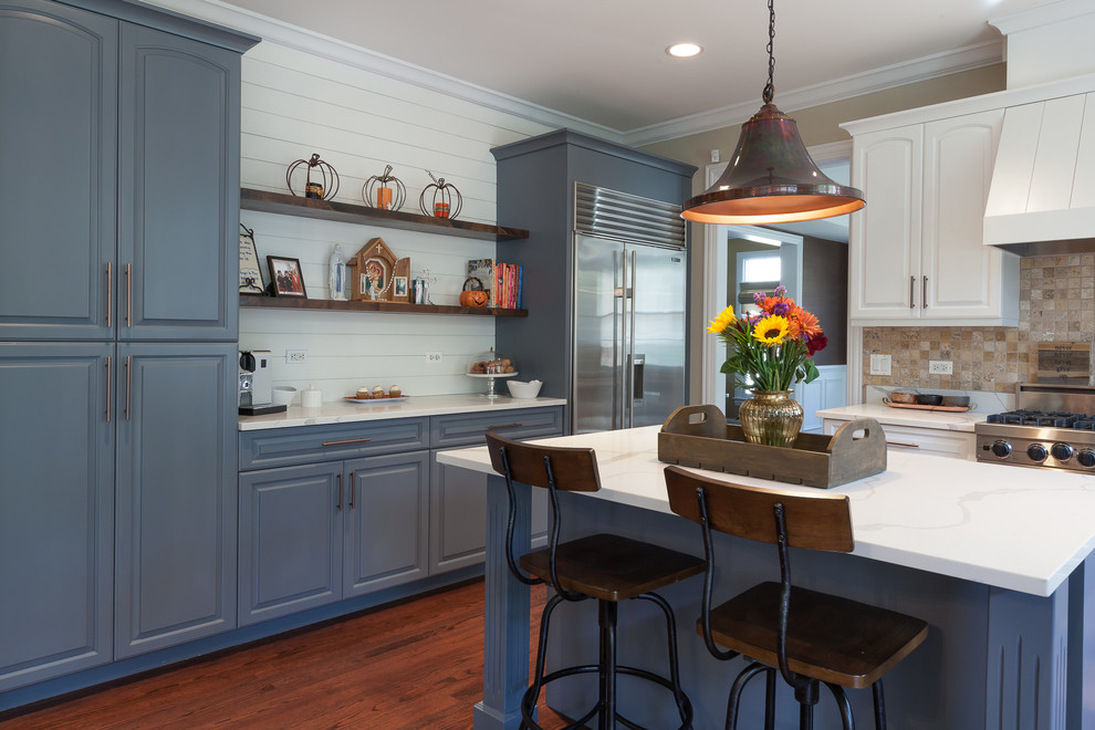 Eat-in kitchen - large cottage u-shaped medium tone wood floor and brown floor eat-in kitchen idea in Chicago with a farmhouse sink, raised-panel cabinets, blue cabinets, quartz countertops, beige backsplash, porcelain backsplash, stainless steel appliances and an island