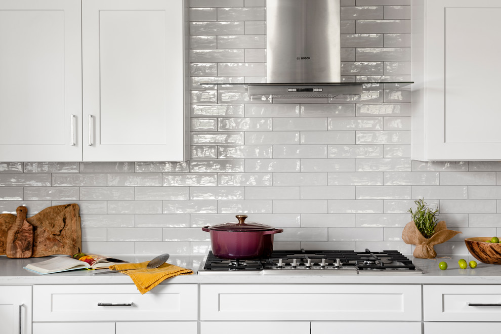 Inspiration for a large farmhouse u-shaped dark wood floor and brown floor eat-in kitchen remodel in DC Metro with a farmhouse sink, recessed-panel cabinets, white cabinets, quartz countertops, white backsplash, subway tile backsplash, stainless steel appliances, an island and white countertops