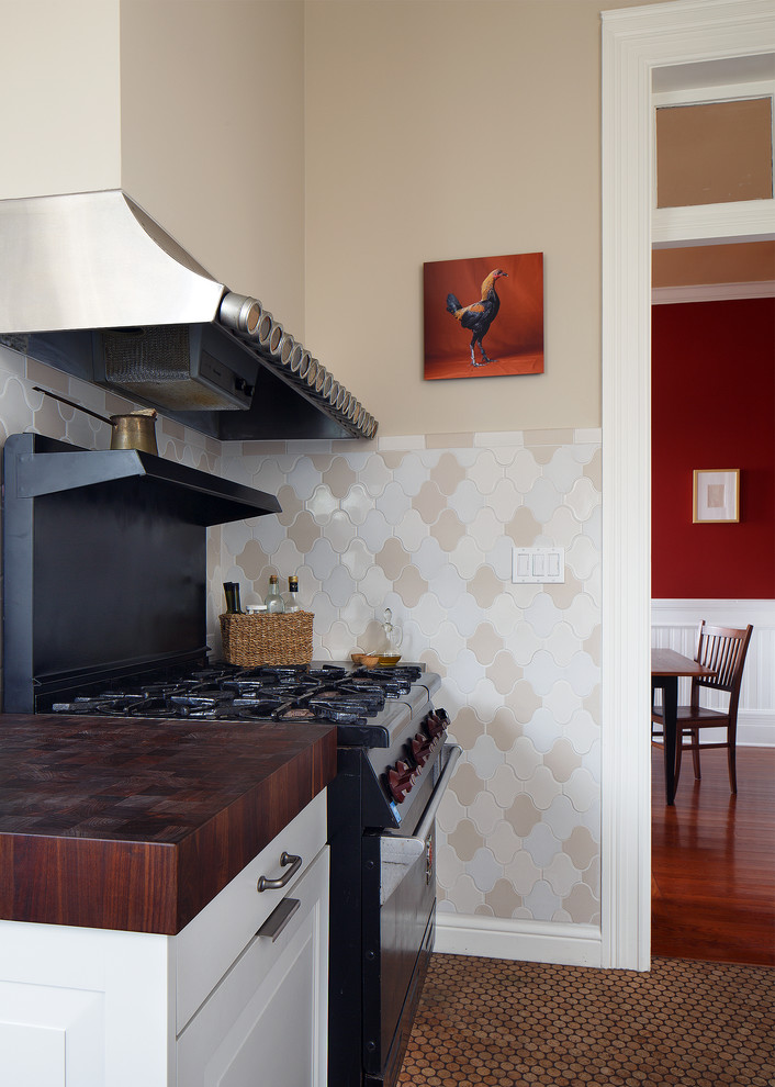 Inredning av ett lantligt mellanstort, avskilt l-kök, med en undermonterad diskho, luckor med upphöjd panel, vita skåp, bänkskiva i kvarts, stänkskydd i keramik, rostfria vitvaror, korkgolv, en halv köksö, flerfärgad stänkskydd och brunt golv
