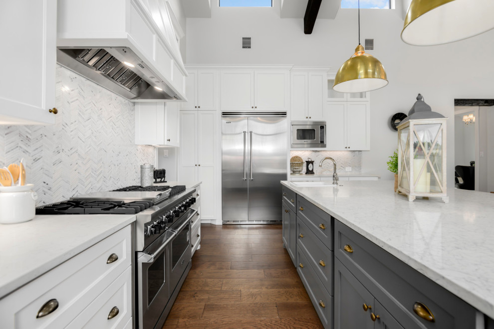 Bild på ett mellanstort lantligt vit vitt kök, med en rustik diskho, luckor med infälld panel, vita skåp, marmorbänkskiva, vitt stänkskydd, stänkskydd i porslinskakel, rostfria vitvaror, mörkt trägolv, en köksö och brunt golv