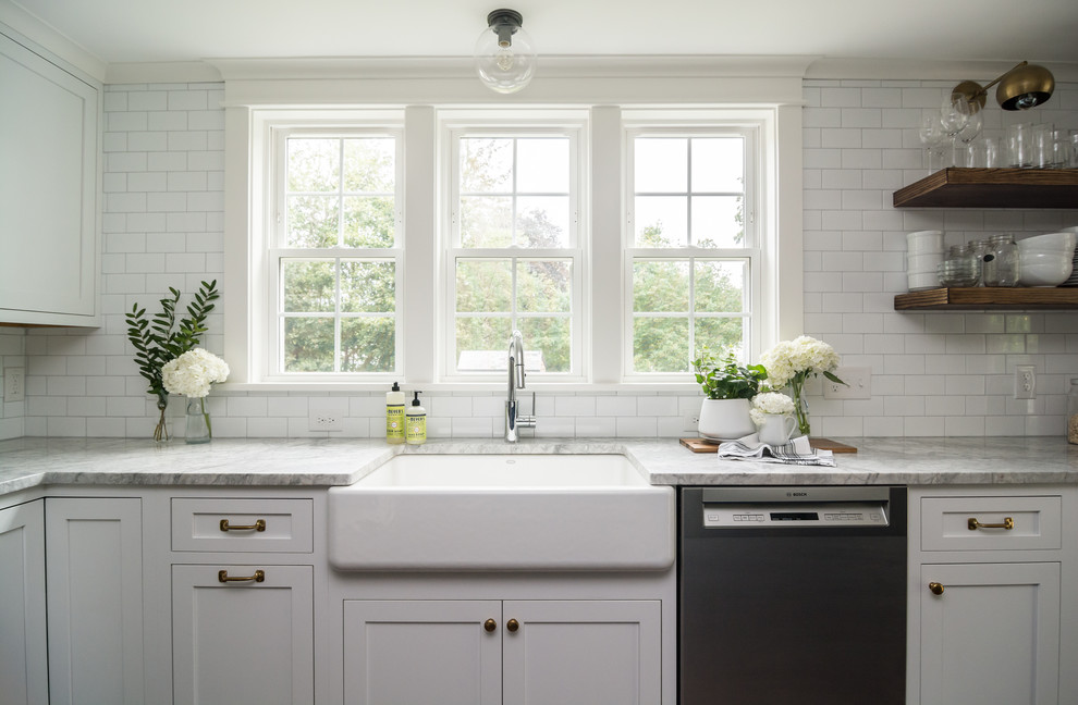 Mid-sized farmhouse l-shaped dark wood floor and brown floor eat-in kitchen photo in Boston with a farmhouse sink, shaker cabinets, white cabinets, quartzite countertops, white backsplash, ceramic backsplash, stainless steel appliances, an island and gray countertops