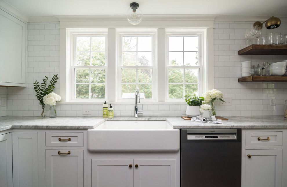 Ejemplo de cocina campestre de tamaño medio con fregadero sobremueble, armarios estilo shaker, puertas de armario blancas, encimera de cuarcita, salpicadero blanco, salpicadero de azulejos de cerámica, electrodomésticos de acero inoxidable, suelo de madera oscura, una isla, suelo marrón y encimeras grises