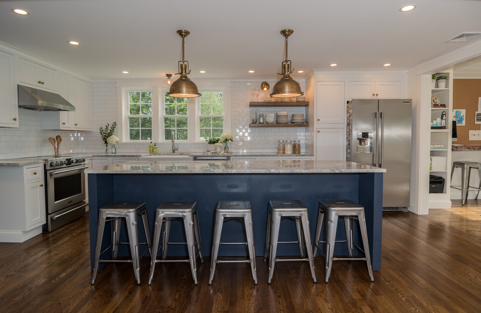 Mid-sized farmhouse l-shaped medium tone wood floor and brown floor eat-in kitchen photo in Boston with a farmhouse sink, shaker cabinets, white cabinets, quartzite countertops, white backsplash, subway tile backsplash, stainless steel appliances, an island and white countertops