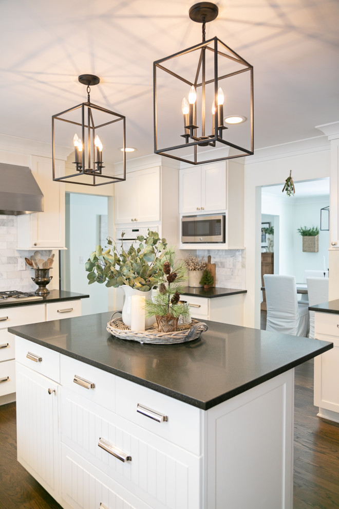 Example of a mid-sized country u-shaped dark wood floor and brown floor eat-in kitchen design in Detroit with a farmhouse sink, shaker cabinets, white cabinets, granite countertops, marble backsplash, stainless steel appliances, an island and black countertops