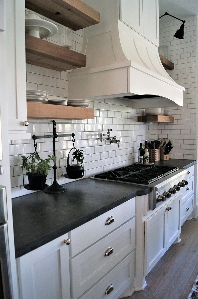 Exempel på ett mellanstort lantligt svart svart kök, med skåp i shakerstil, vita skåp, bänkskiva i koppar, en köksö, en rustik diskho, vitt stänkskydd, stänkskydd i tunnelbanekakel, rostfria vitvaror, ljust trägolv och gult golv