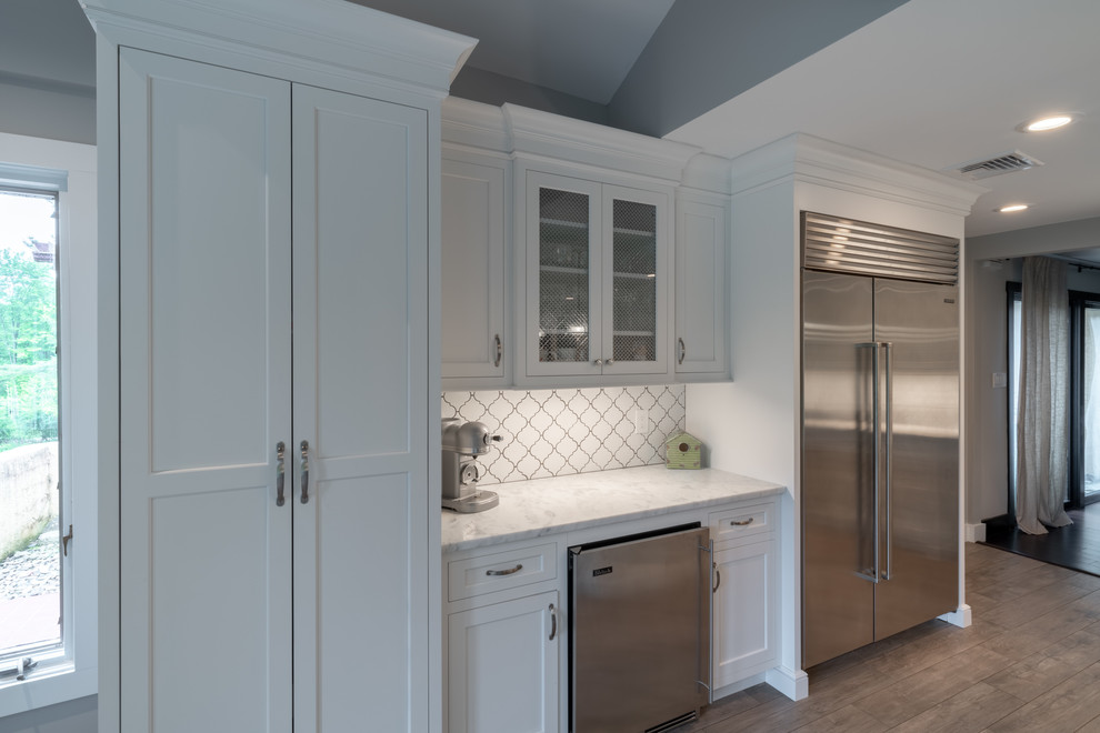 Kitchen - huge modern medium tone wood floor and gray floor kitchen idea in Other with a farmhouse sink, shaker cabinets, white cabinets, marble countertops, white backsplash, porcelain backsplash, stainless steel appliances, an island and white countertops