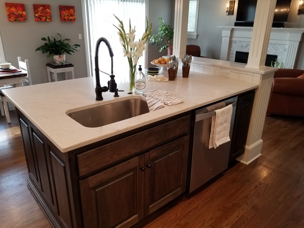 Exempel på ett mellanstort lantligt kök och matrum, med en undermonterad diskho, vita skåp, bänkskiva i kvarts, vitt stänkskydd, stänkskydd i keramik, rostfria vitvaror, mörkt trägolv, en köksö och brunt golv